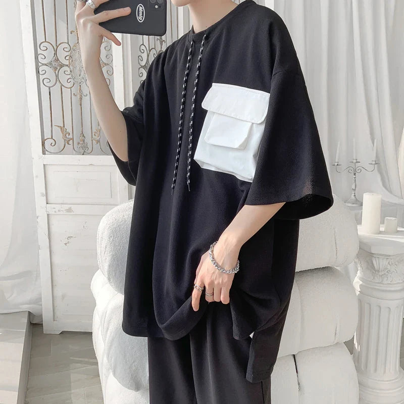 Oversized black t-shirt with a large white pocket, featuring a streetwear Harajuku style, suitable for summer 2023.