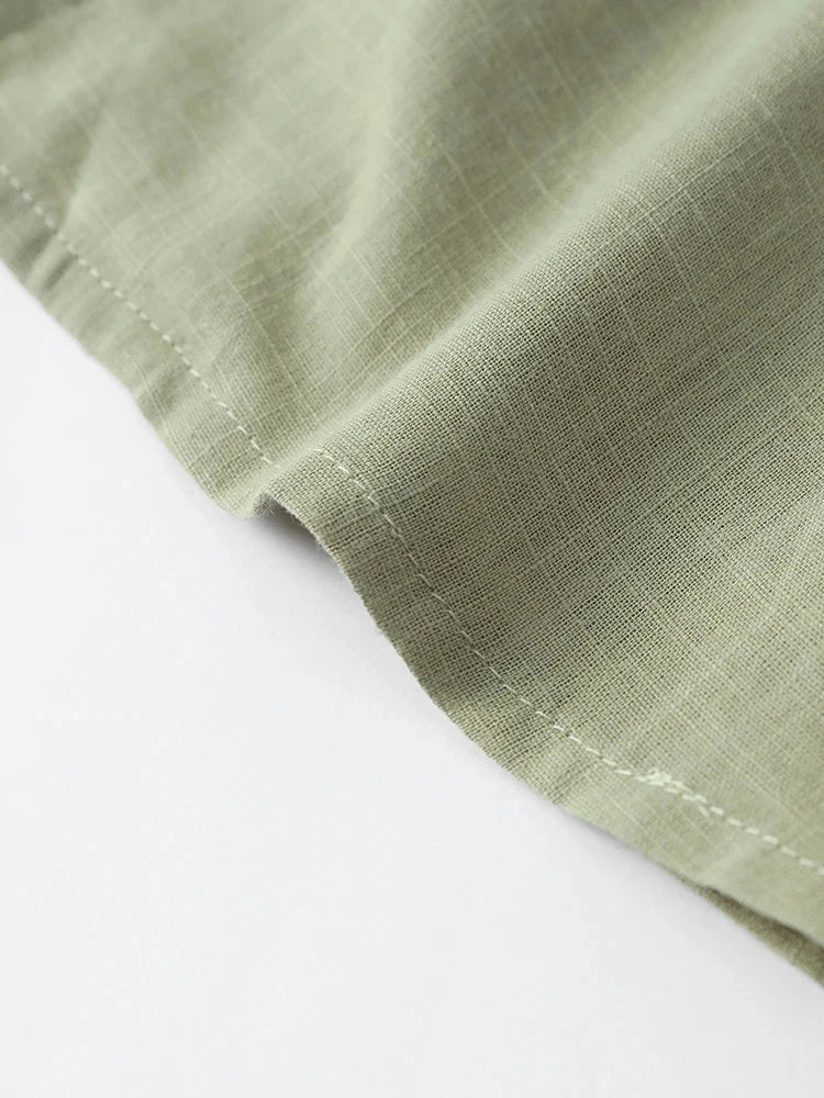 Close-up of lightweight green fabric of a women’s loose V-neck long sleeve top for spring 2024.