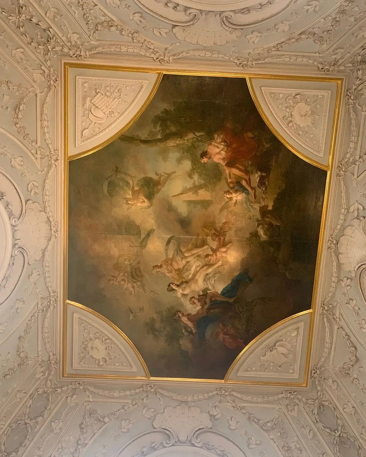 Ceiling art with classical painting and ornate architectural details.