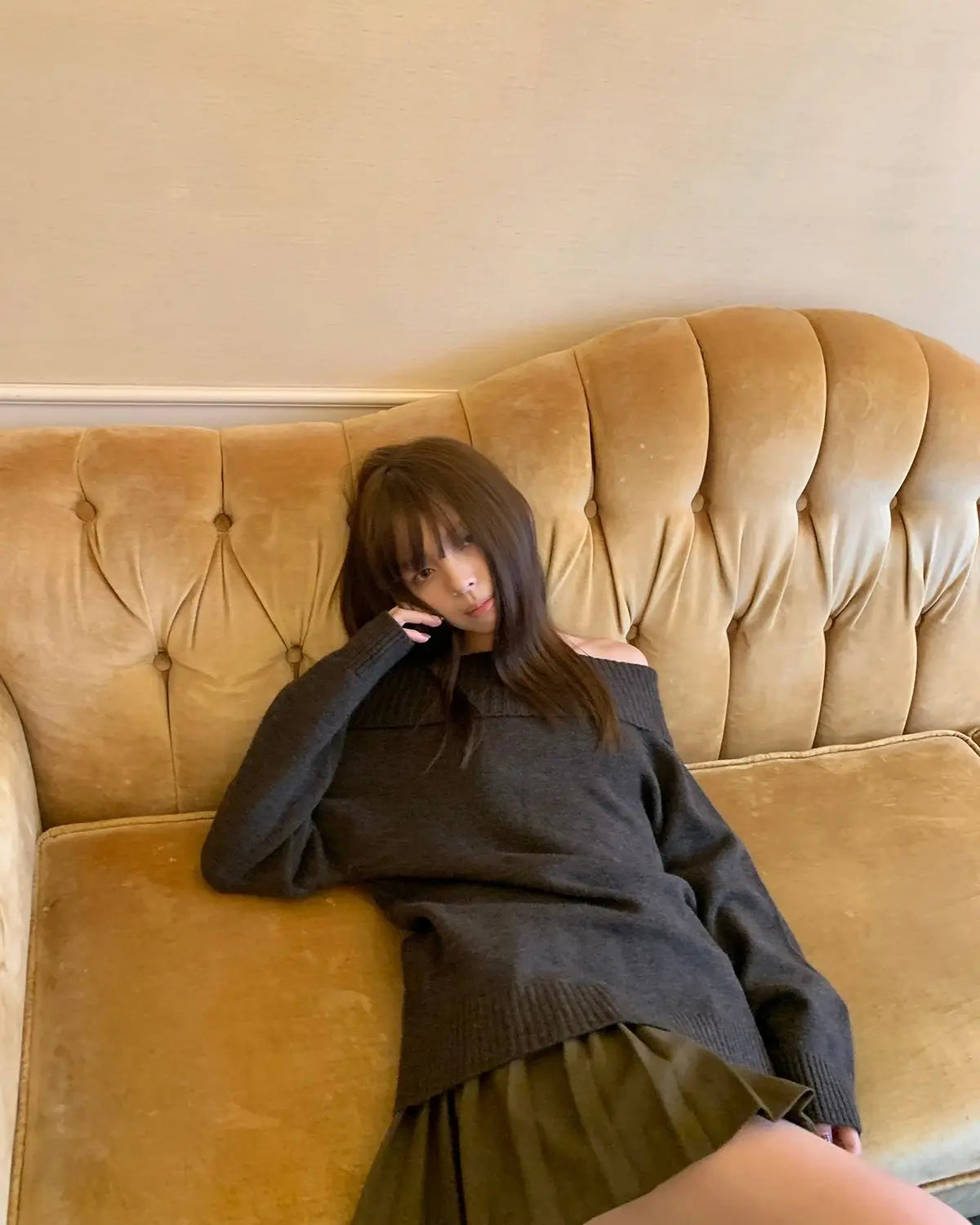 Vintage Japanese style off-shoulder knitwear, Y2K long sleeve jumper with slash neck in solid color, modeled casually on a sofa.