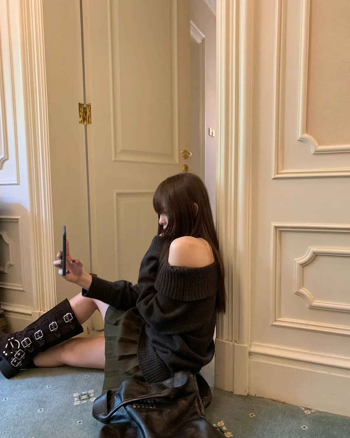 Woman wearing a vintage Japanese style off-shoulder black sweater with long sleeves, sitting casually indoors.