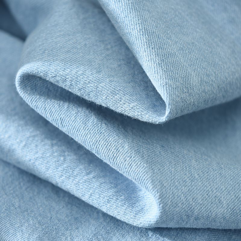 Soft light blue denim fabric close-up for men's long sleeve shirt.