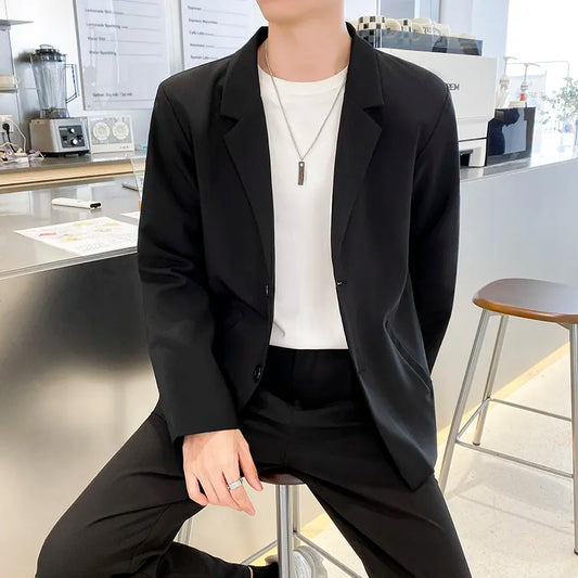 Men's black blazer with lapel, two buttons, suitable for business casual, shown at a modern workspace.