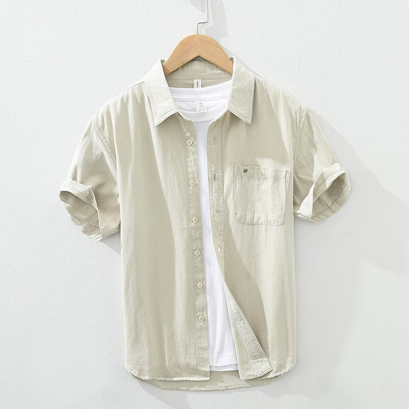 Men's short sleeve cotton casual shirt with patch pockets, embroidery, and button-up design in solid color.