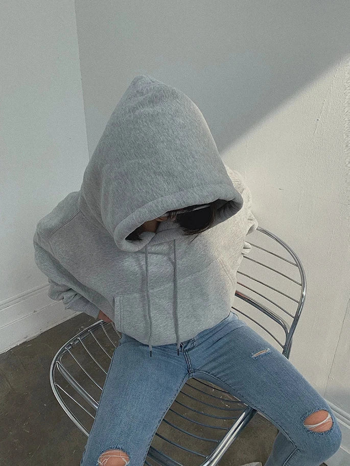 Women's casual grey hoodie and blue jeans outfit on metal chair.