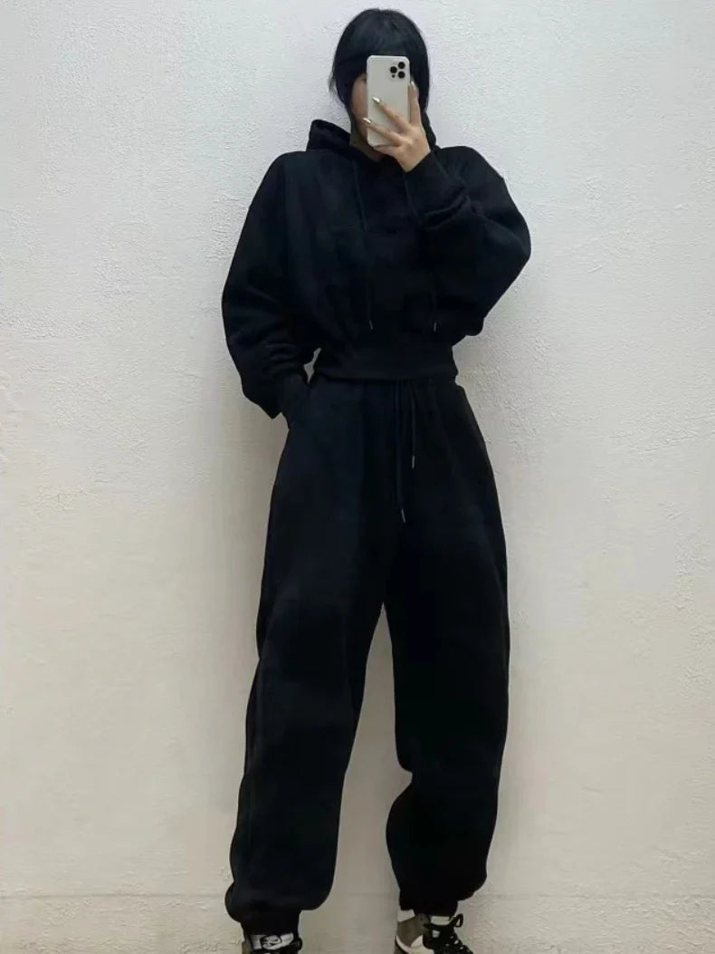 Women's black fleece casual tracksuit with hooded sweatshirt and ankle-length sweatpants.