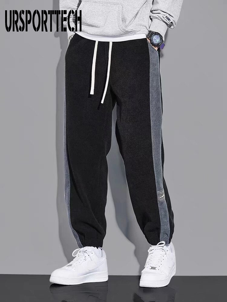 URSPORTTECH black joggers with gray side stripes, elastic waist, and drawstring closure, styled for hip hop streetwear.