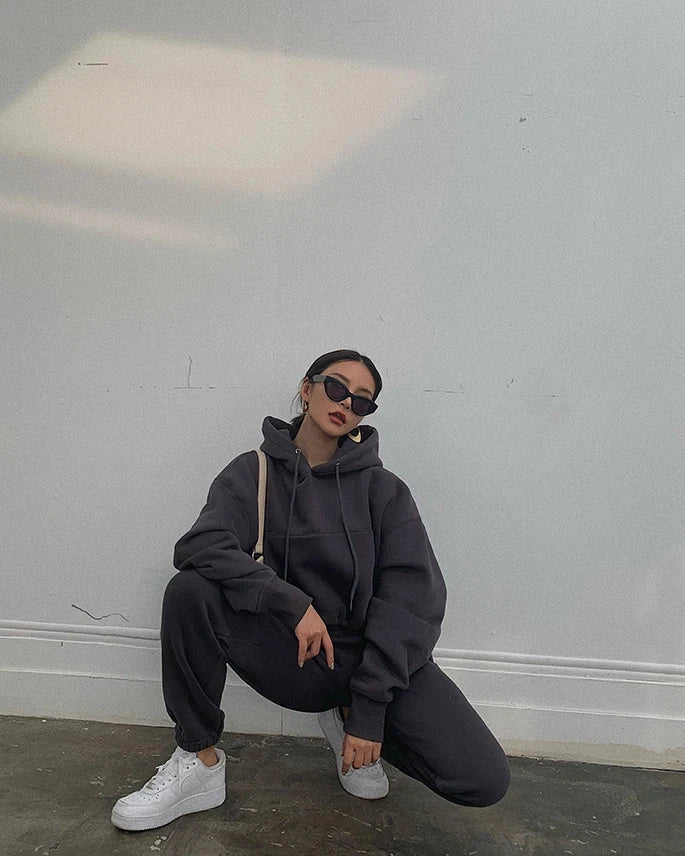 Women's casual hoodie and sweatpants fleece tracksuit set in dark color, featuring a hooded pullover and ankle-length pants, ideal for autumn and winter.